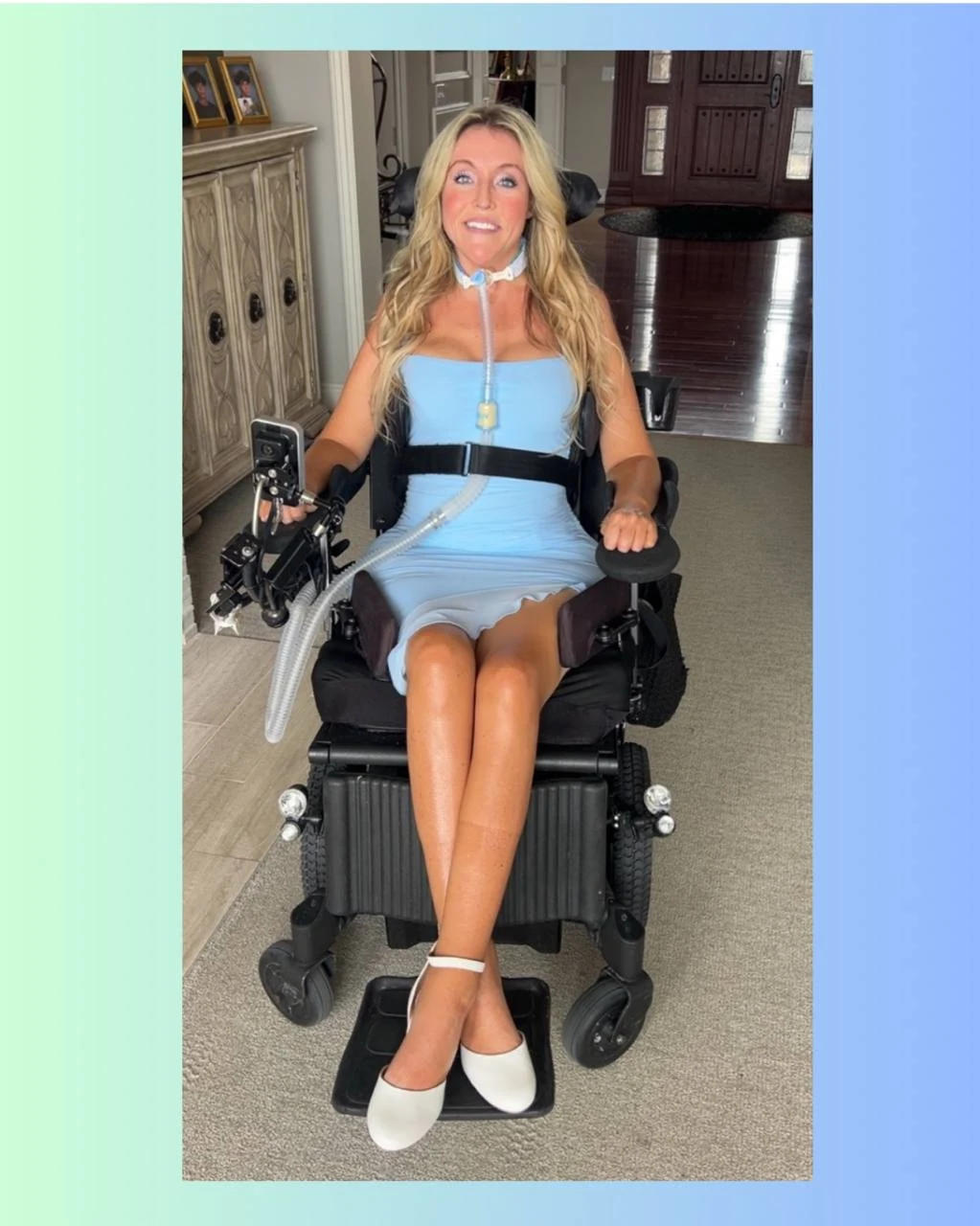 Laura Michelle smiling in a light blue dress while seated in her wheelchair.
